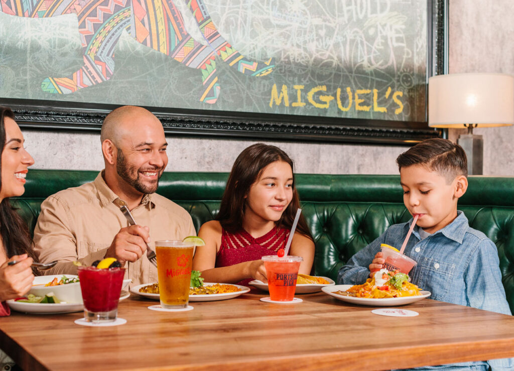 family smiling and eating together at Miguels